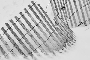 damaged thin wooden fence leaning in the snow
