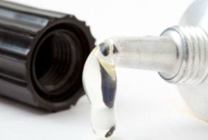 an open, dripping container of clear adhesive