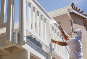 person spray painting balcony railing white