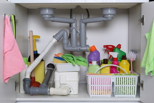 open cabinet under sink with cleaning supplies