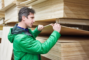 a person in green looking at plywood