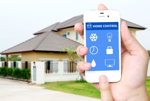 A hand holding a smart phone in front of a house.