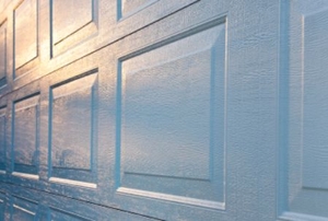 A new aluminum garage door with the sunrise reflecting off of the white surface.
