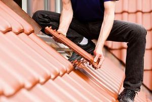 Tiler covering roof with new tile