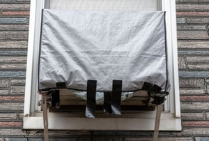 a window AC unit covered with a tarp