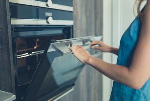 A woman opens an oven door.