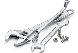 Several wrenches and screws in a pile against a white background.