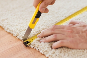 hands measuring and cutting carpet