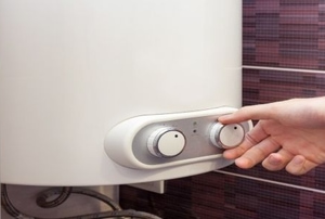 A hand adjusts the knob on a wall heater.