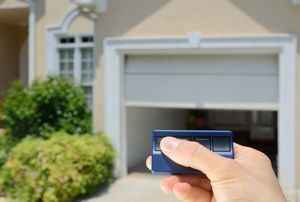 holding a garage door opener with a house in the background.