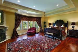 A luxurious bedroom featuring a large, Persian rug and a bay window.