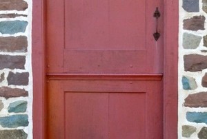 a red two-part dutch door in a stone wall