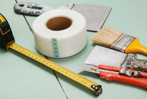 Drywall joint tape on a mint table with other painting tools.