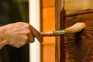 Painting a stain on a wood exterior.