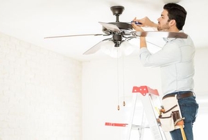 a man fixing a ceiling fan
