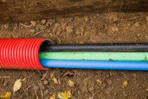 Three colored cables inside of red conduit, ready to be buried.