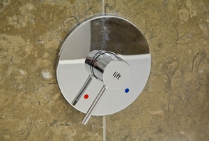 A chrome shower fixture attached to a granite wall.