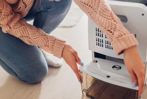 a woman takes the water tank off her dehumidifier