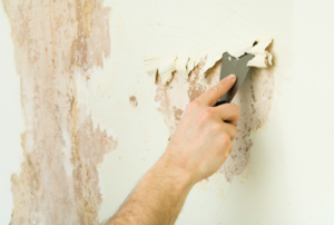 A man removes wallpaper.