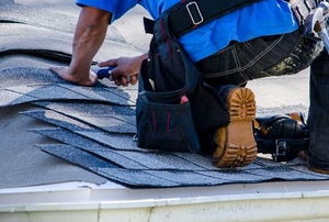 worker on roof replacing asphalt shingles