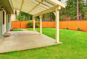 a wood structure over a small patio in a yard