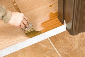 A man uses a brush near painter's tape.