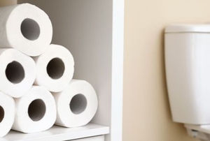 toilet paper stacked in a wooden cube in a bathroom