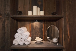 A rustic bathroom with rolled towels and candles.