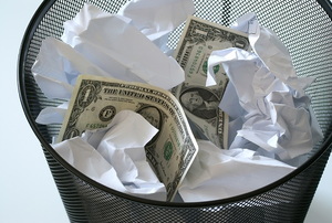 dollar bills and crumpled paper in a garbage can