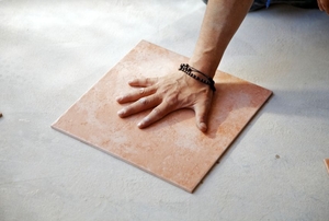 A man lays down porcelain tile flooring.