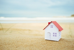 A tiny white cardboard house sitting on the beach.