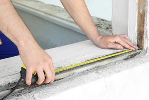 Man measuring opening in wall for a window.