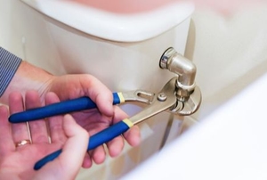 hands using wrench to adjust toilet pipe