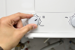 hand adjusting temperature dial on tankless water heater