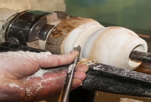 Someone using a wood turning parting tool.