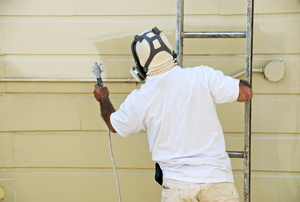 A homeowner painting his siding.