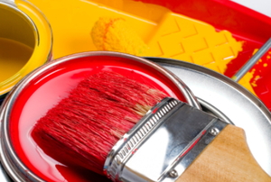 A paintbrush, paint tray and paint ready for use.