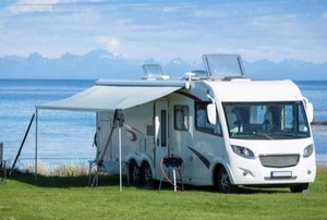An RV with an awning parked by water