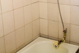 Dirty tile and yellowed stains in a bathtub.