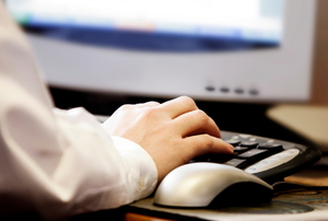 A computer user typing on a desktop keyboard.