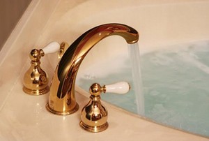 A gold-toned faucet running water into a bathtub.