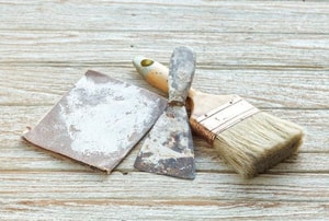 sandpaper, a scraper, and a paintbrush on wood