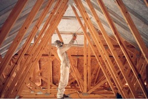 A home improvement professional spraying interior radiation control coating on the underside of a roof.