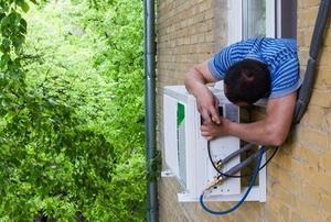 man fixing window ac unit