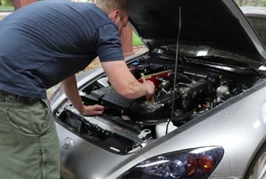 A man looks at a car's engine.