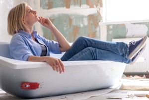 woman in a bathtub looking at remodeling project