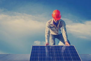 A construction worker on a roof with a solar panel.