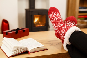 A wood burning oven in the background with Christmas socks and a book in the foreground. 