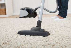 a woman vacuuming a cream colored area rug