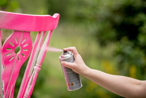 A woman spray paints furniture.